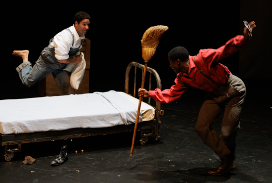 Two men chase each other on stage during a theatrical production