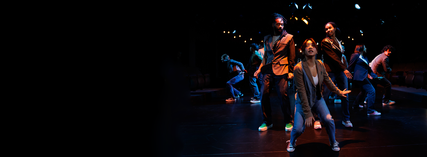 A group of students dance in formation during a theater production